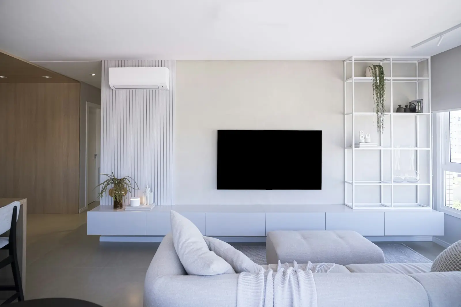 A bright living room with a white wall-mounted air conditioning unit above the sofa